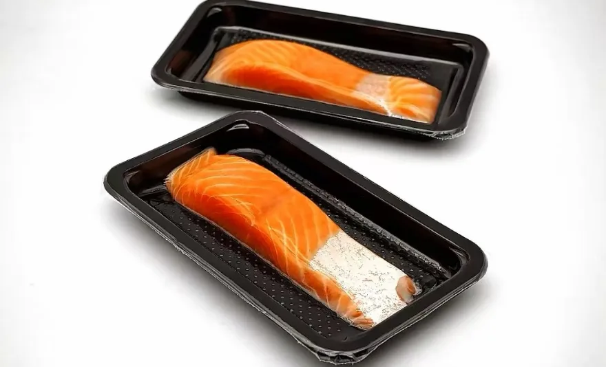 Salmon fillets vacuum skin packed on black trays